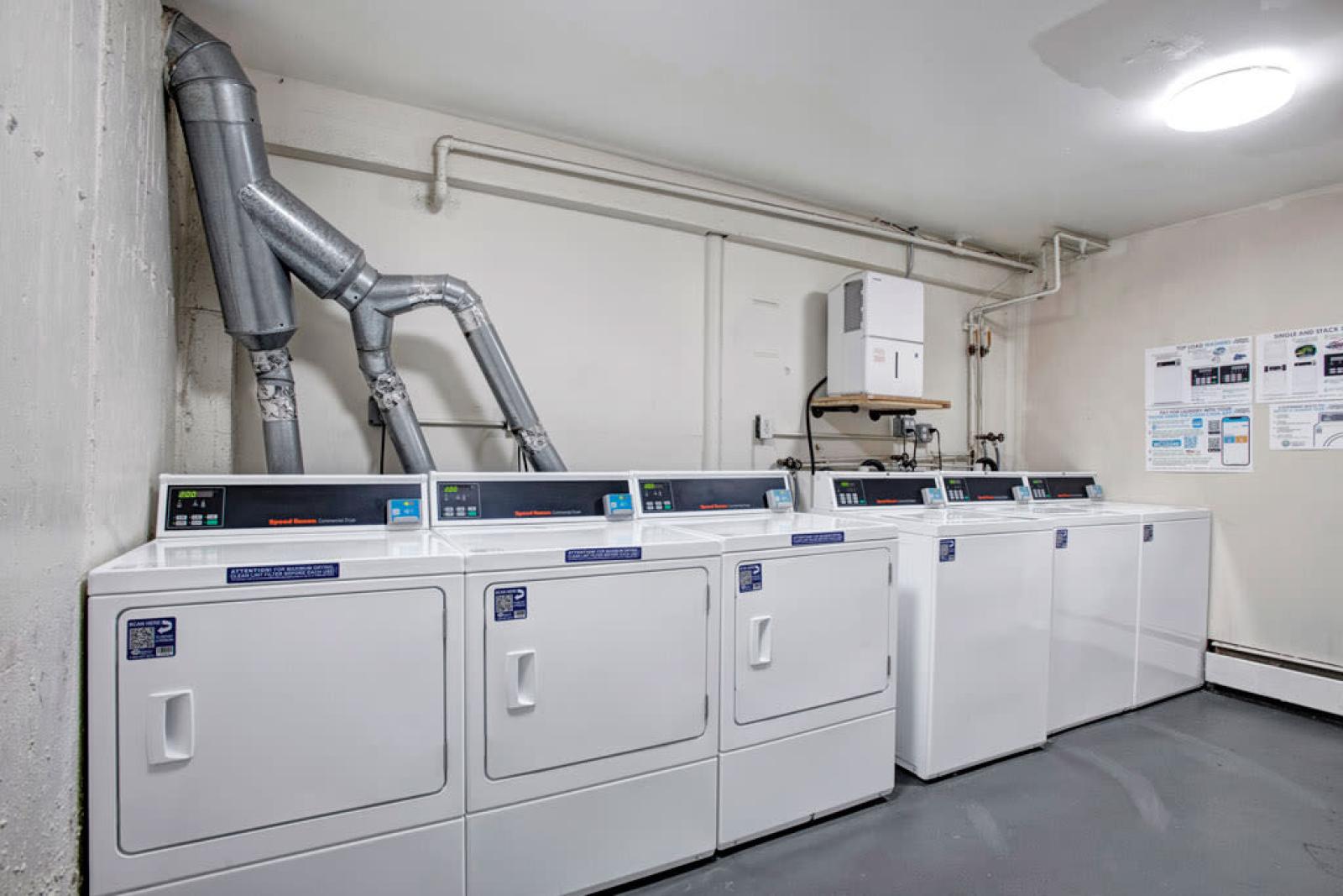 Laundry facility at The Manors Apartments with multiple modern washers and dryers for resident convenience.