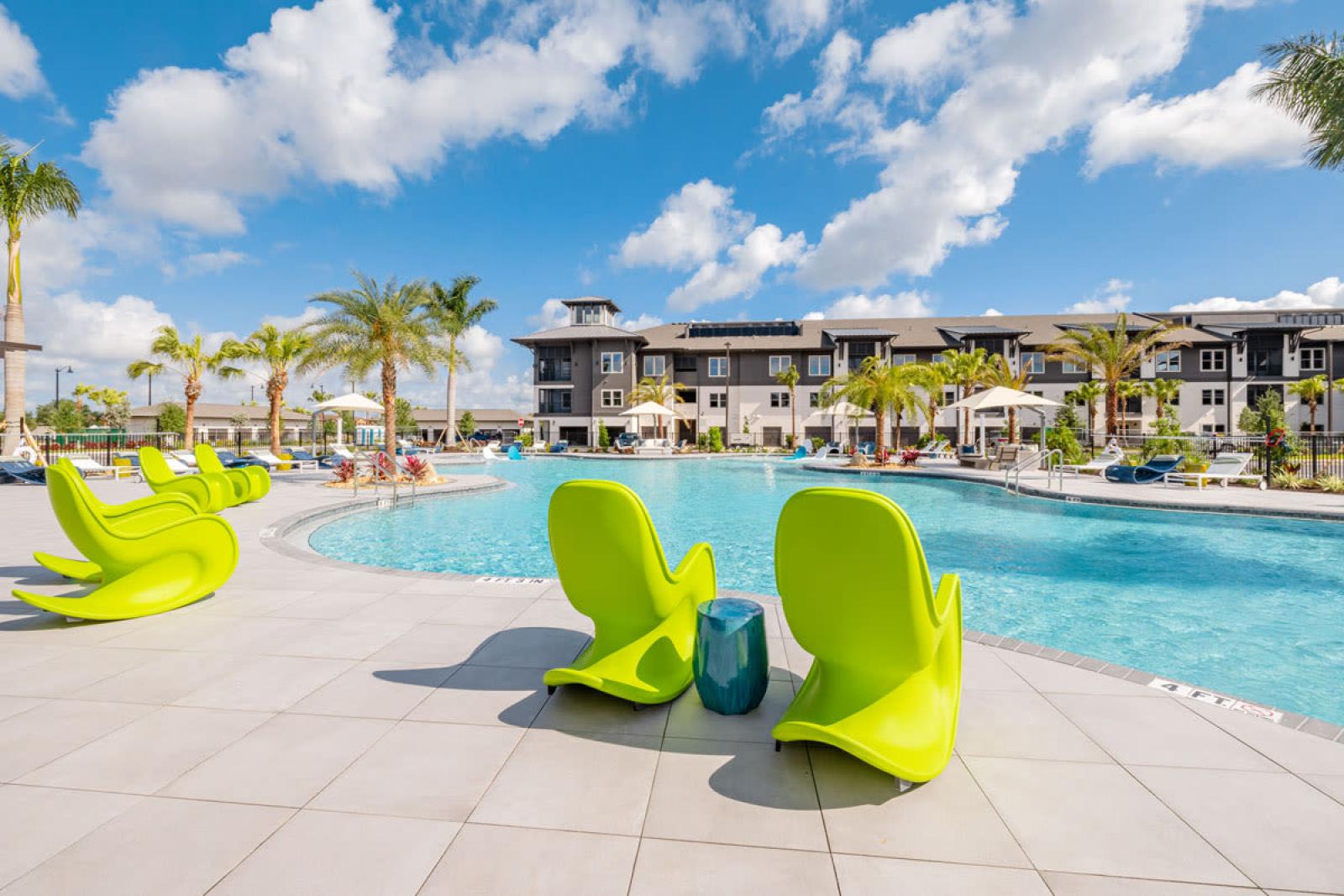 "Spacious resort-style pool with vibrant green lounge chairs at Tropia Wellen Park Apartments."