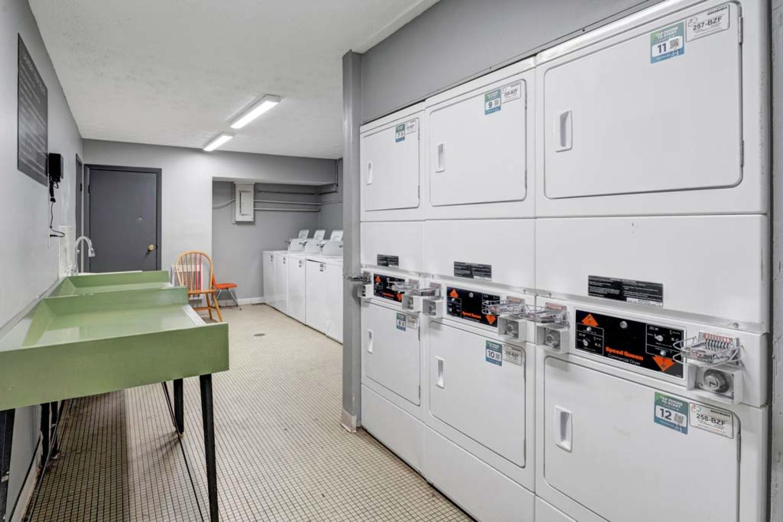 Well-maintained laundry room with washing machines, dryers, and folding stations for resident convenience.