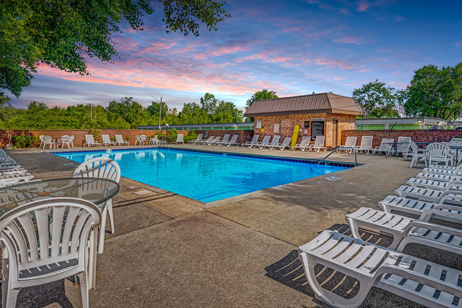 A spacious outdoor pool area at Wilson Plaza Apartments, featuring ample lounge chairs and shaded seating options.