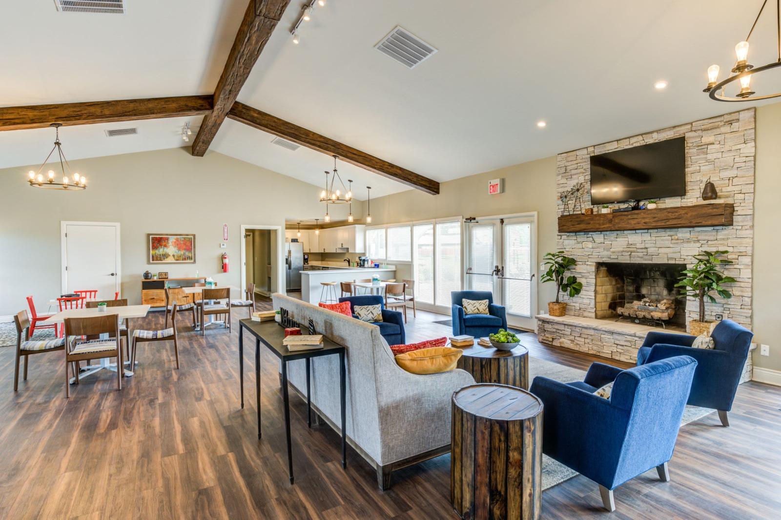 "Modern clubhouse at Worthington Meadows Apartments featuring cozy seating, a fireplace, and natural light from large windows."