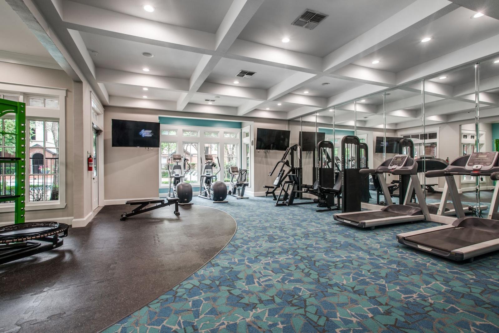 A spacious fitness center featuring treadmills, weight machines, and free weights with a modern blue and gray design.