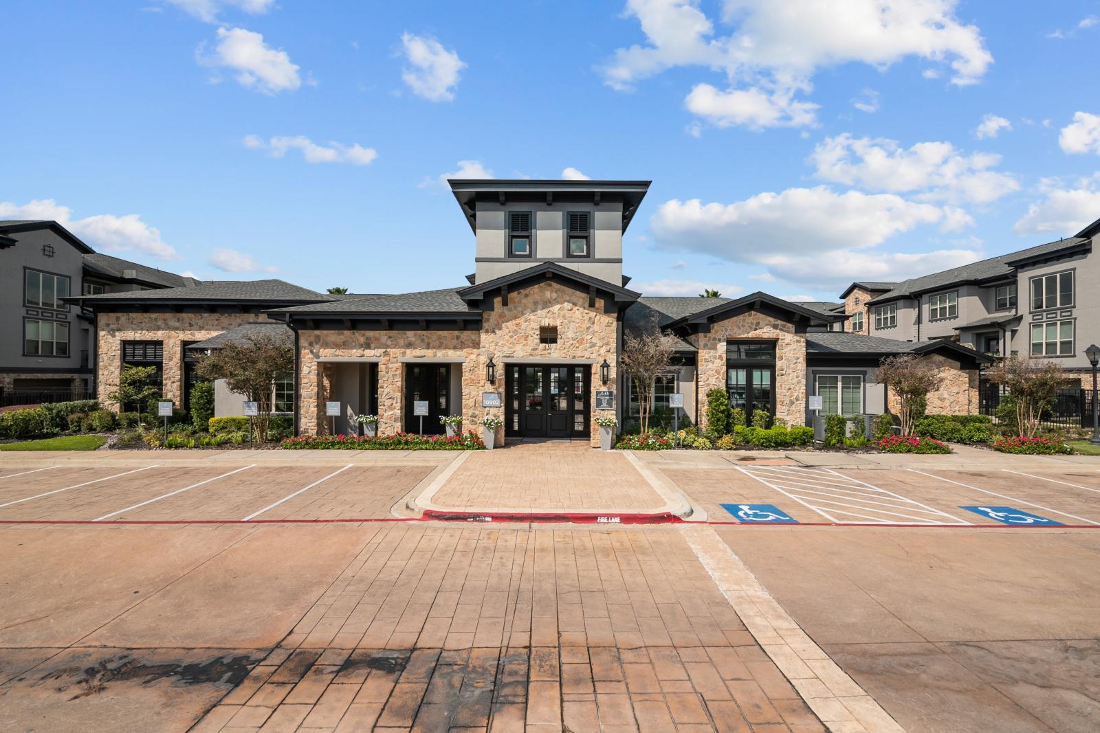 Beautifully designed leasing office with a stone facade, landscaped flower beds, and accessible parking.