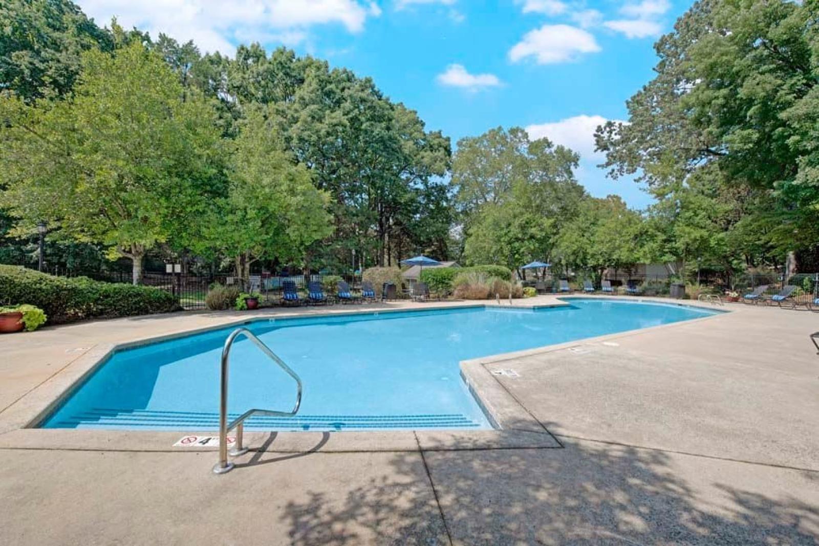 A large pool with crystal-clear water, surrounded by nature and ample seating.