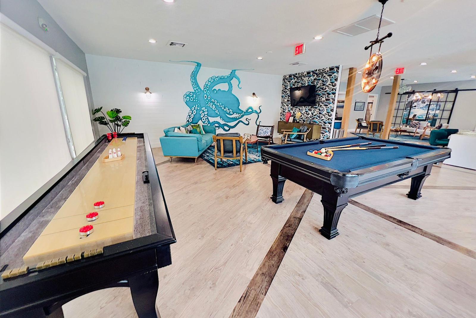 Spacious and modern community lounge featuring a pool table, seating areas, large windows, and a vibrant teal accent wall, creating a lively and inviting space for social activities.