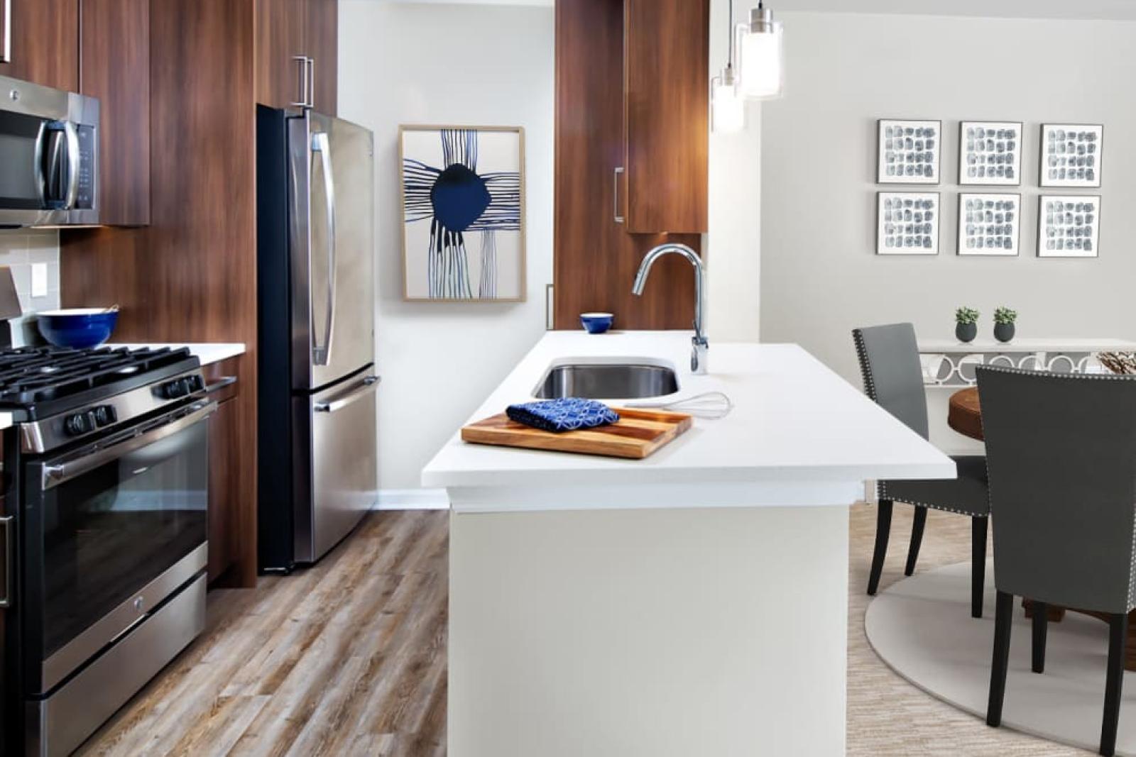 A contemporary kitchen with stainless steel appliances, wood cabinetry, and a quartz countertop island, leading into a stylish dining area.