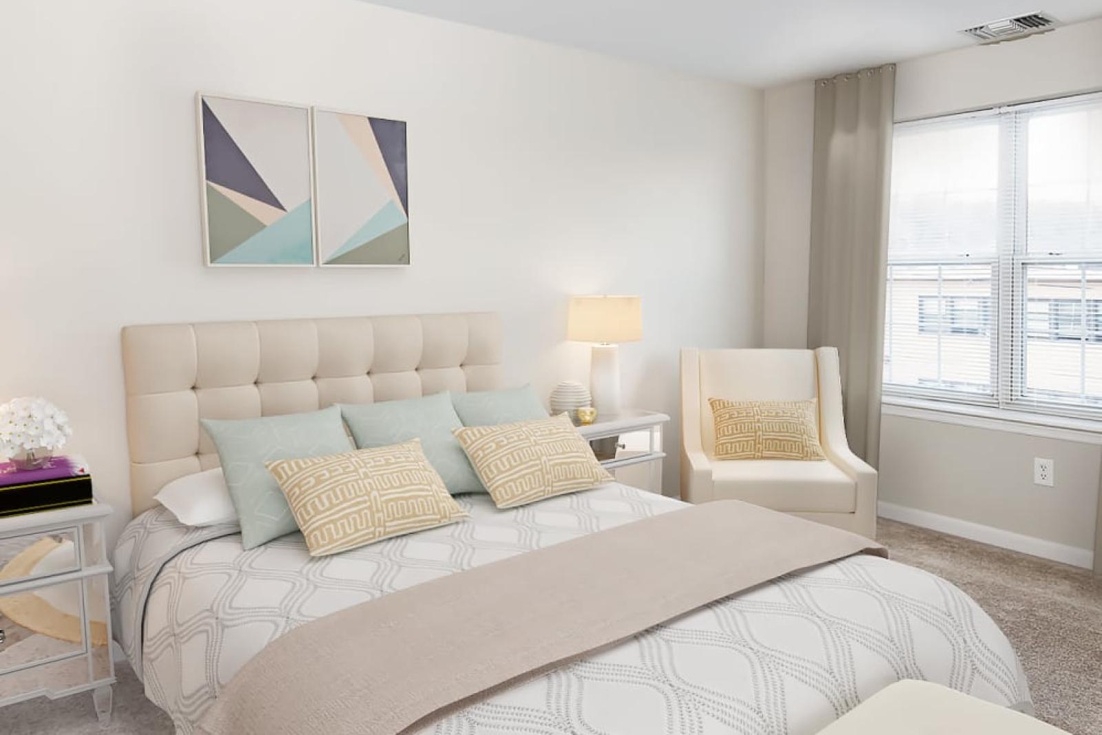 A bright and spacious bedroom with a plush, tufted headboard, elegant neutral-toned bedding, and modern décor at The Mark at Mamaroneck Luxury Apartments.