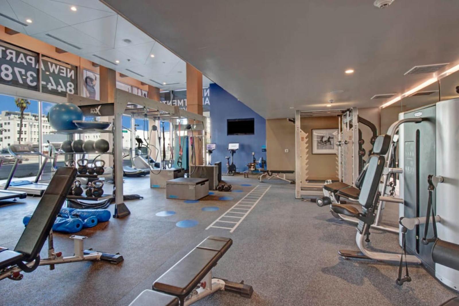Expansive gym with state-of-the-art machines and a vibrant mural at The Pacific Luxury Apartments.