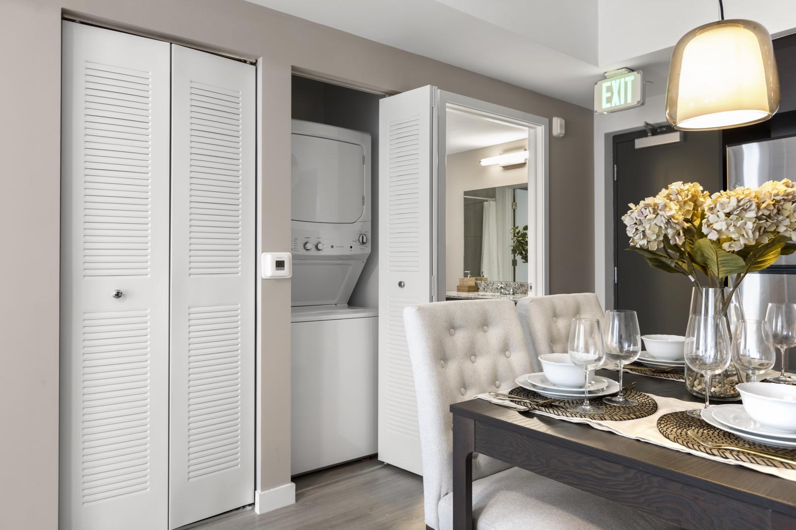 A built-in washer and dryer neatly concealed within a modern closet, located in a Pine Ridge Luxury Apartments unit.