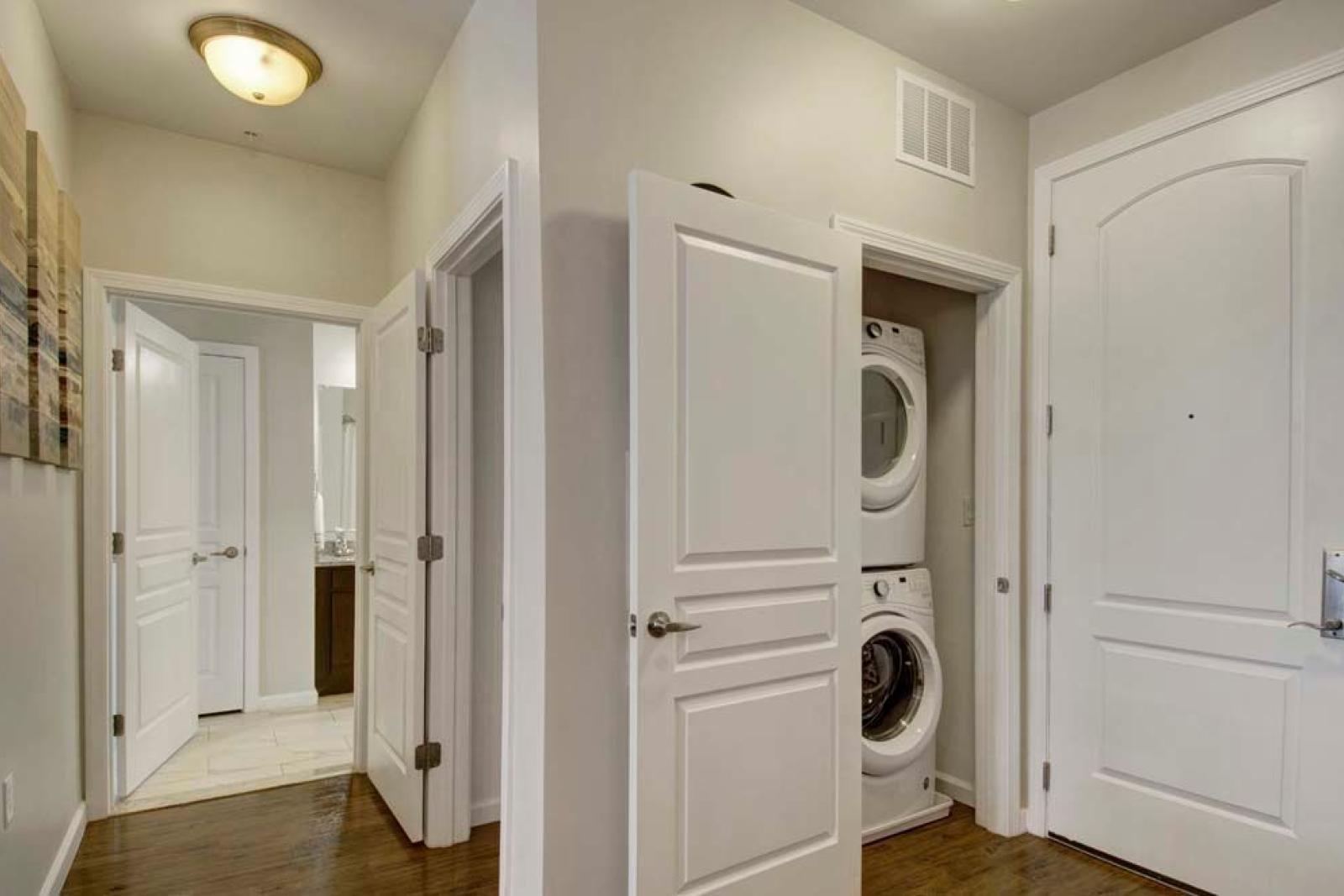A utility space with a stacked washer and dryer conveniently located near the entryway of the apartment.