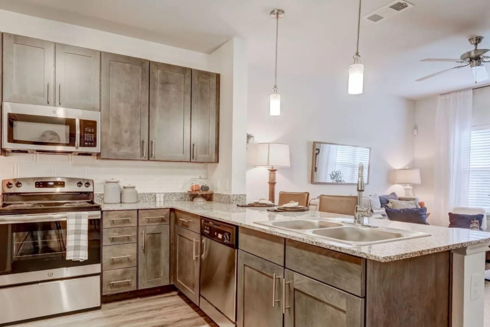 Upscale kitchen with stainless steel appliances, granite countertops, and pendant lighting at The Emerson at Forney Luxury Apartments.