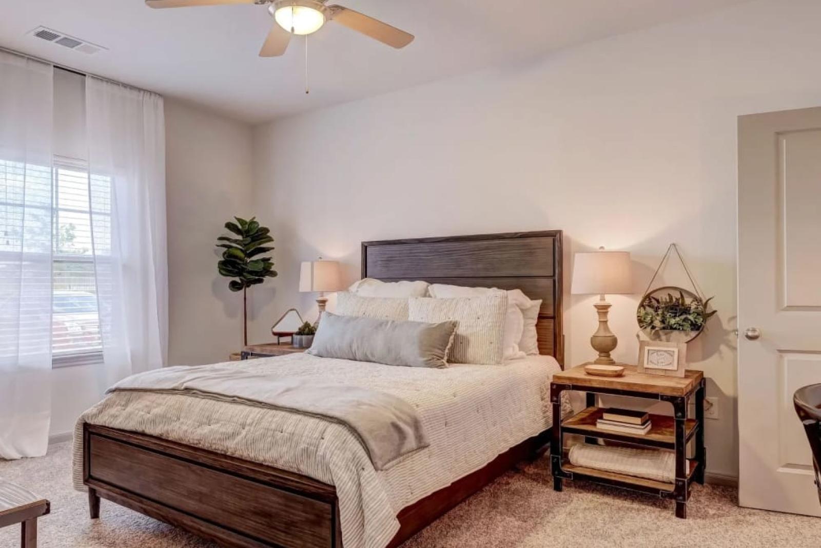 Spacious master bedroom with elegant decor, plush carpeting, and large windows at The Emerson at Forney Luxury Apartments.