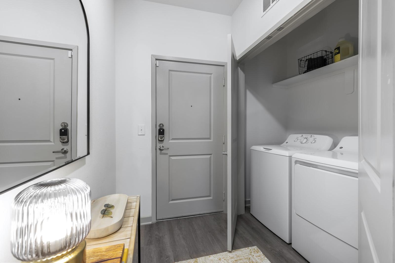 A convenient in-unit laundry space with a stacked washer and dryer, built-in shelving, and sleek modern finishes.
