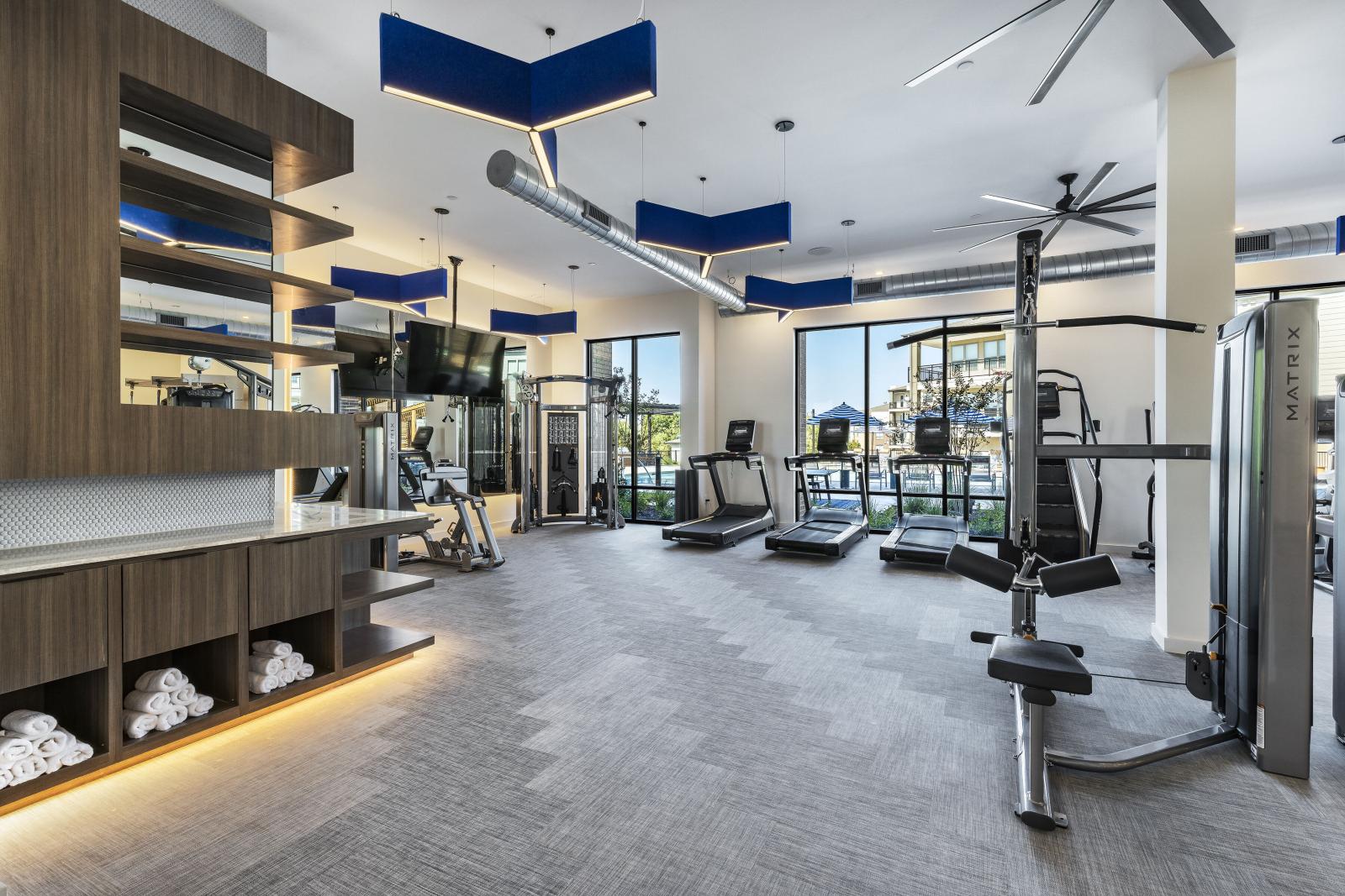A bright and spacious gym with treadmills, weight machines, and large windows that overlook the pool area for an energizing workout experience.