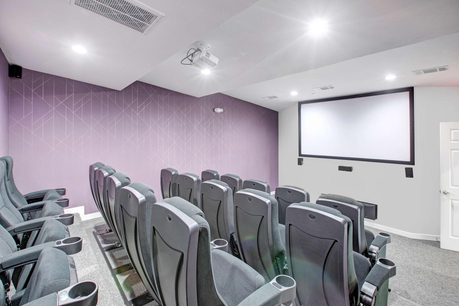 Theater-style media room with multiple rows of cushioned seating and a large projection screen.