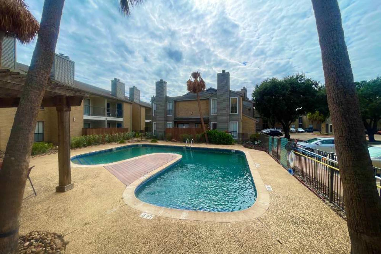 A relaxing poolside ambiance with palm trees and a well-maintained deck at The Oaks of Westchase Apartments, offering a serene environment for residents.