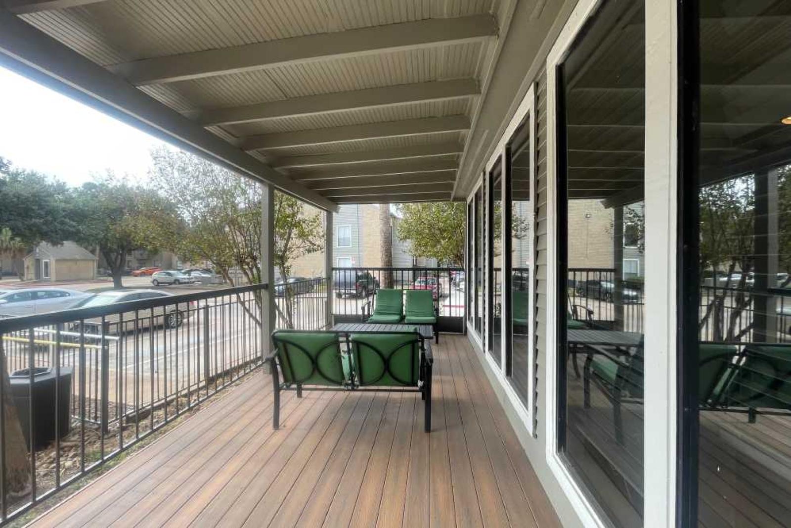 A covered outdoor lounge area with comfortable green seating at The Oaks of Westchase Apartments, perfect for relaxing while enjoying the view.