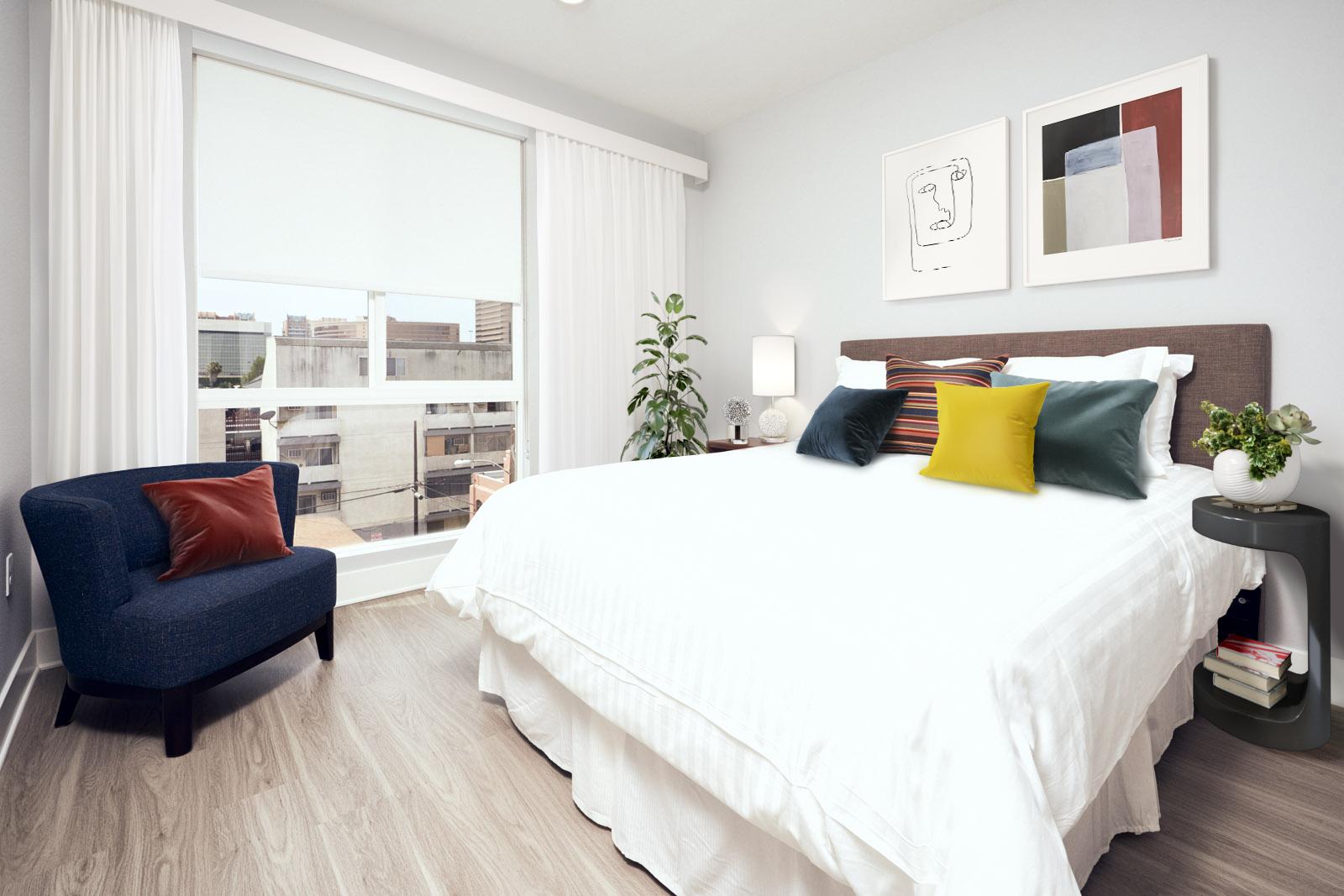Bright bedroom with large window, modern decor, and wood-style flooring.