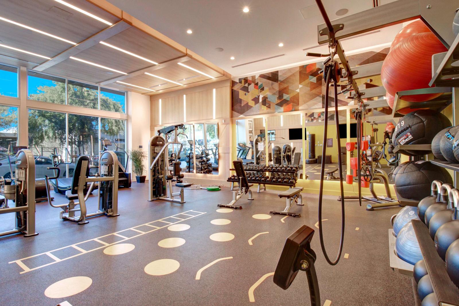 Fully equipped fitness center with large windows and various workout equipment.