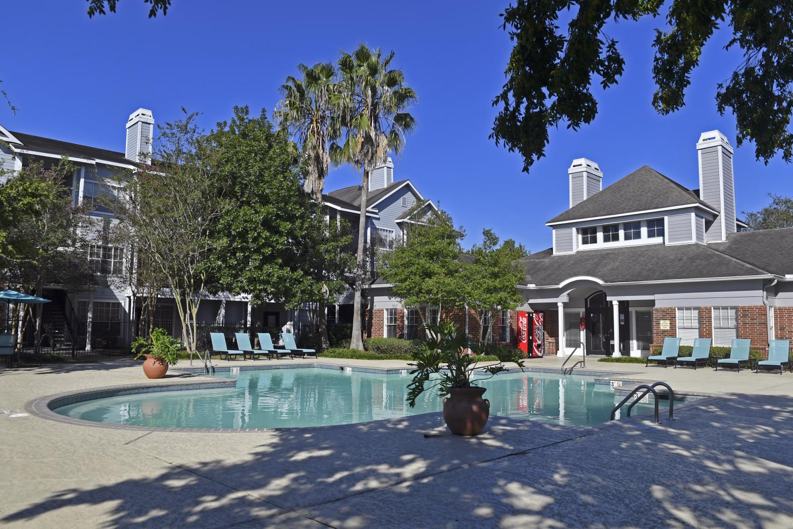 Resort-style swimming pool with lounge chairs and shaded patio seating at Summer Creek Apartments in San Antonio, TX.