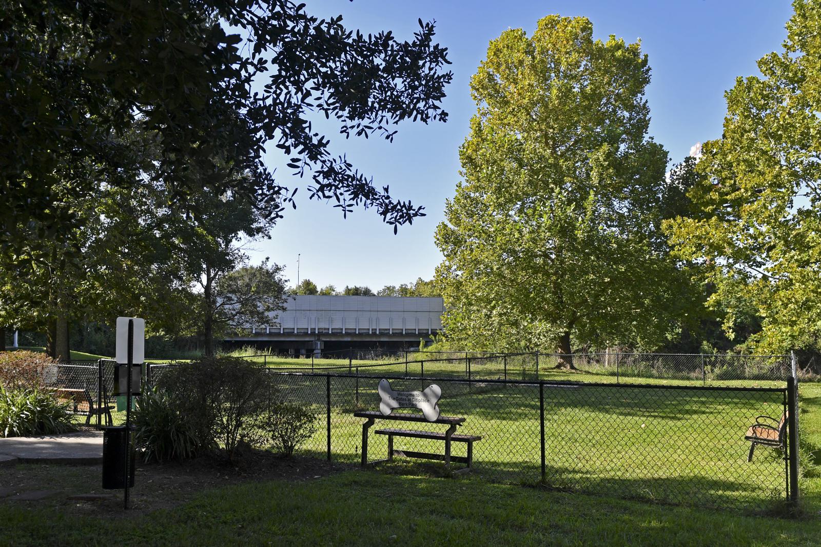 Large pet park with mature trees, grassy area, and seating at Gates at Citiplace apartment community