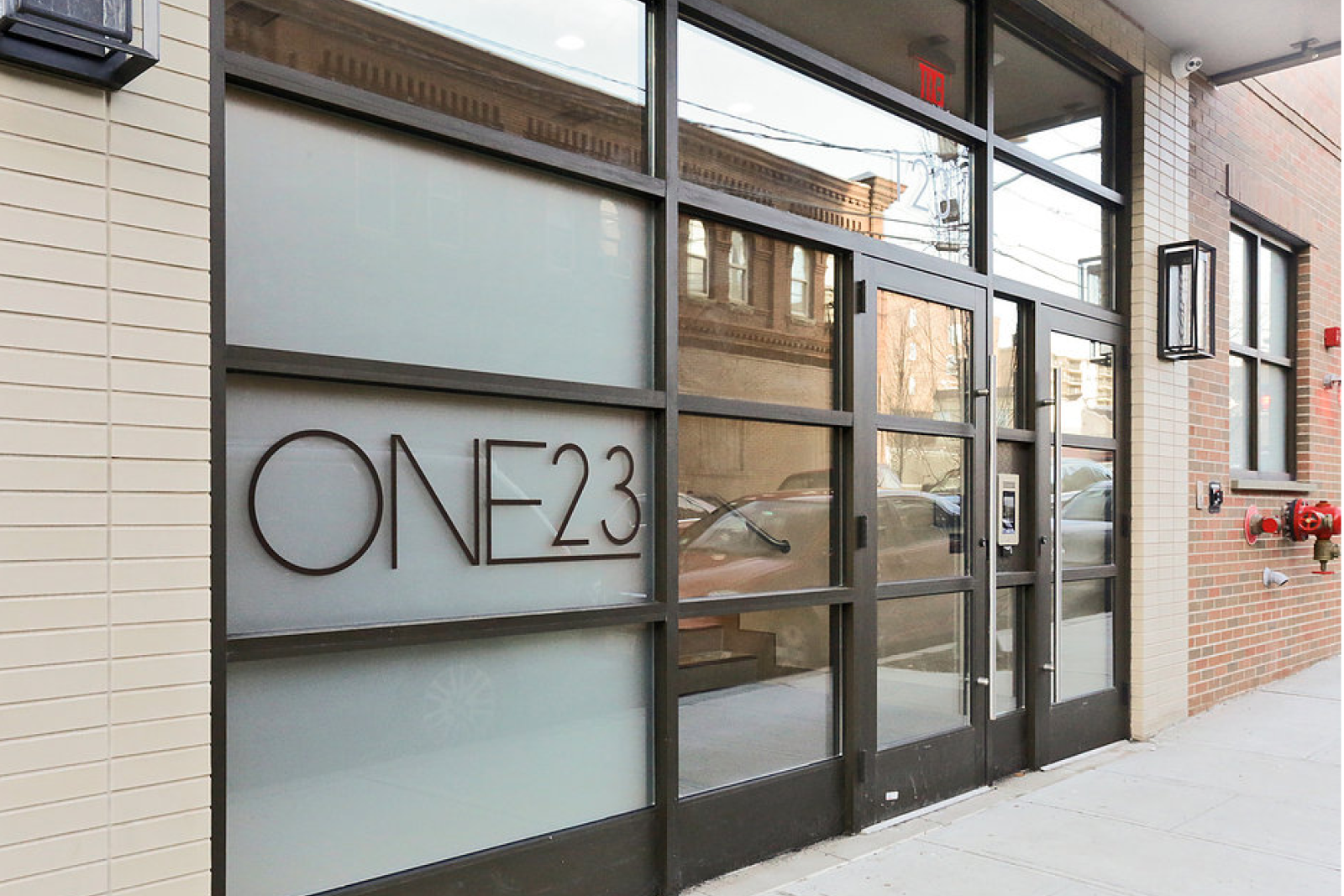 Exterior glass entrance with One23 signage at One23 Apartments in Union City, NJ