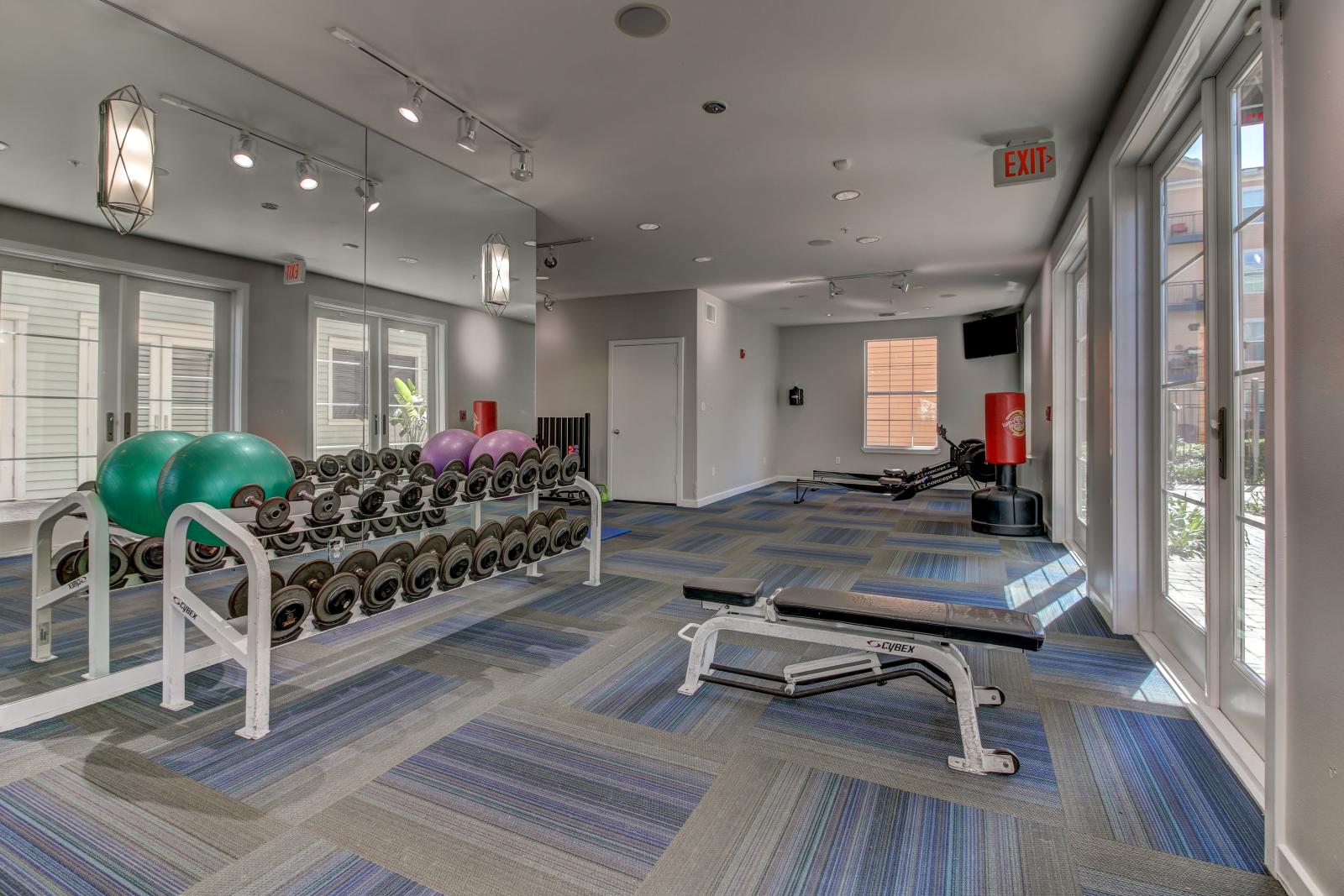 The Saulet apartment gym with dumbbell rack, flat bench, and strength training equipment in New Orleans, LA.