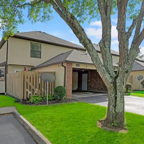 The exterior view of a townhome with a private fenced patio area and lush green grass.