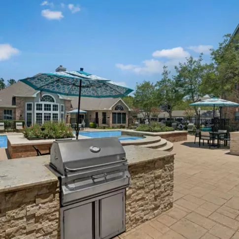 Outdoor grilling station with adjacent seating areas and a view of the pool.