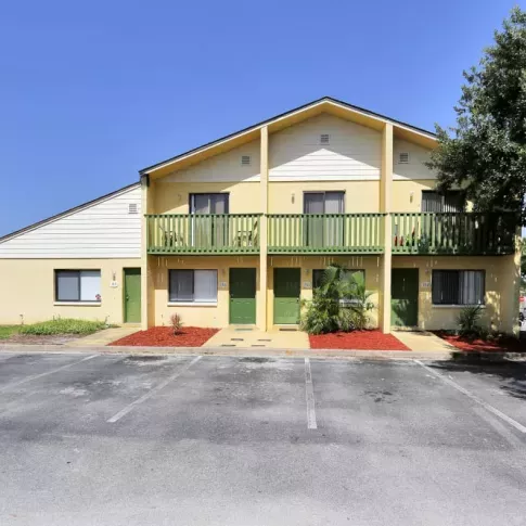 Exterior of Townhome Building: A vibrant yellow townhome building with green doors, small balconies, and neatly landscaped surroundings.