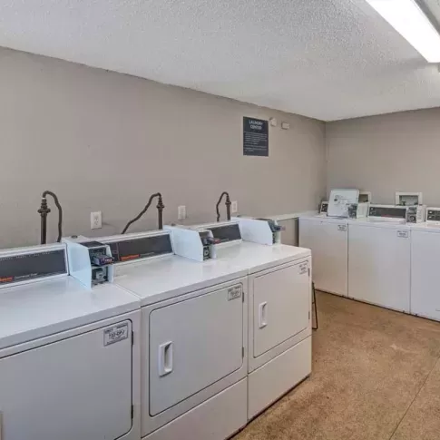 A clean and well-lit laundry room equipped with multiple washers and dryers for resident use. This image highlights the convenient on-site laundry facilities at Broadview Oaks Apartments.