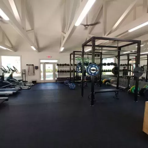 A spacious fitness center at Chatsworth Apartments in Chamblee, GA, featuring modern workout equipment, including treadmills, free weights, and power racks, under vaulted ceilings with natural light.
