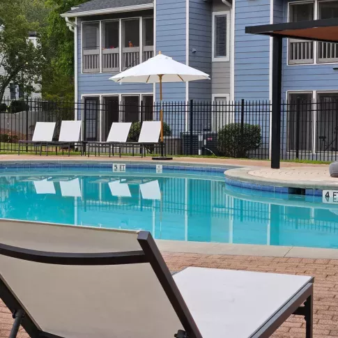 Refreshing poolside at Chatsworth Apartments with sun loungers and scenic views of the property.