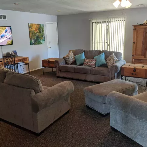 A cozy clubhouse with comfortable sofas, a dining area, and a mounted TV, creating an inviting space for residents to gather and relax