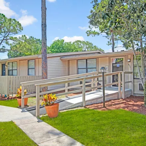 A close-up view of an accessible ramp leading to an apartment entrance adorned with decorative plants.
