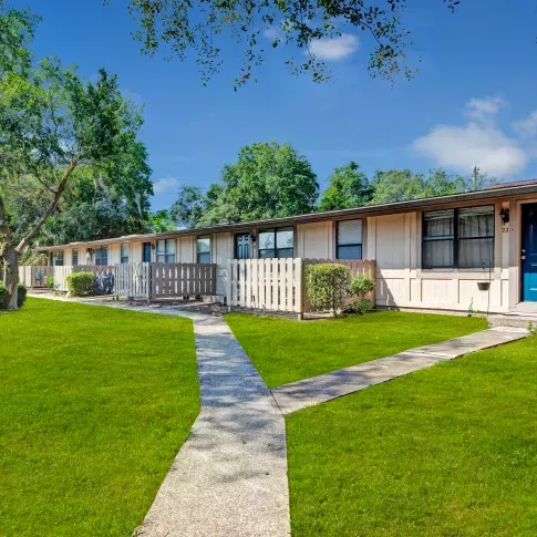 A Y-shaped concrete pathway leading to single-story residential units with green lawns and large trees.