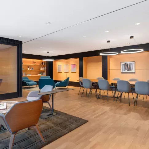 A private dining room with a round marble table, upholstered chairs, and warm wood tones, accented by a sculptural light fixture.