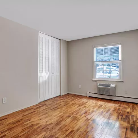 Bright bedroom with hardwood flooring, a large window for natural light, and ample closet space, ideal for restful nights.