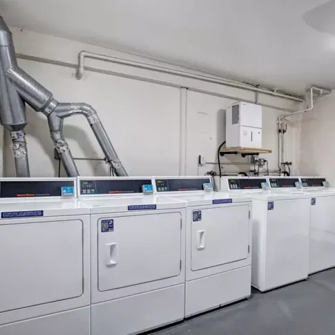 Laundry facility at The Manors Apartments with multiple modern washers and dryers for resident convenience.