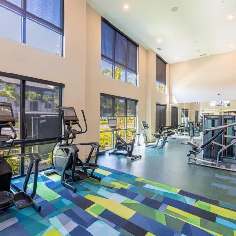 Image 1: Fitness center with modern exercise equipment, including a functional trainer, punching bag, and kettlebells, overlooking landscaped views through large windows.