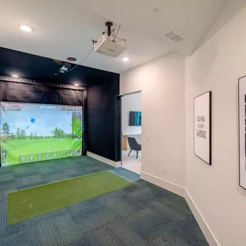 A high-tech golf simulator room at Tropia Wellen Park Apartments, providing an immersive virtual golfing experience for residents.