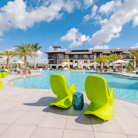 "Spacious resort-style pool with vibrant green lounge chairs at Tropia Wellen Park Apartments."