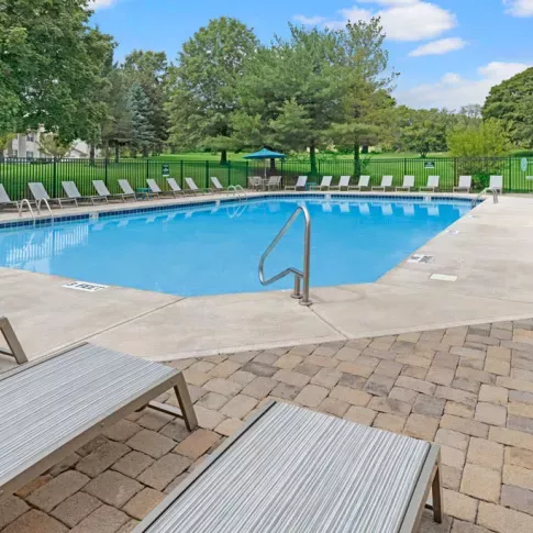 A sparkling outdoor pool with ample lounge chairs and umbrellas, providing a relaxing spot for residents to enjoy the sun.