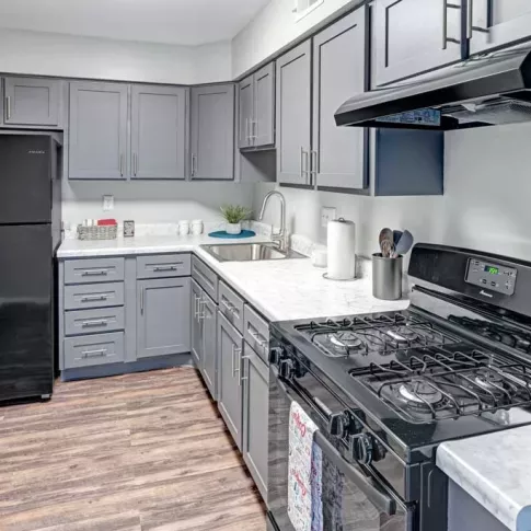 A modern kitchen in a Wilson Plaza apartment with sleek grey cabinets, updated appliances, and hardwood flooring.