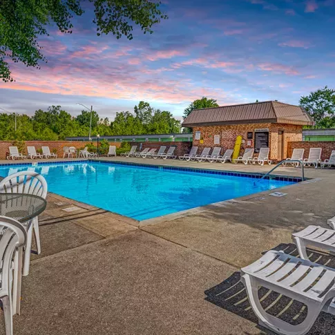 A spacious outdoor pool area at Wilson Plaza Apartments, featuring ample lounge chairs and shaded seating options.