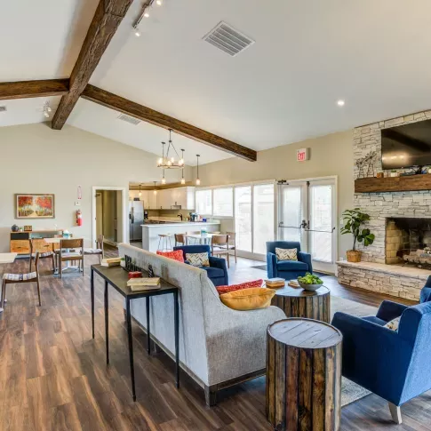 "Modern clubhouse at Worthington Meadows Apartments featuring cozy seating, a fireplace, and natural light from large windows."