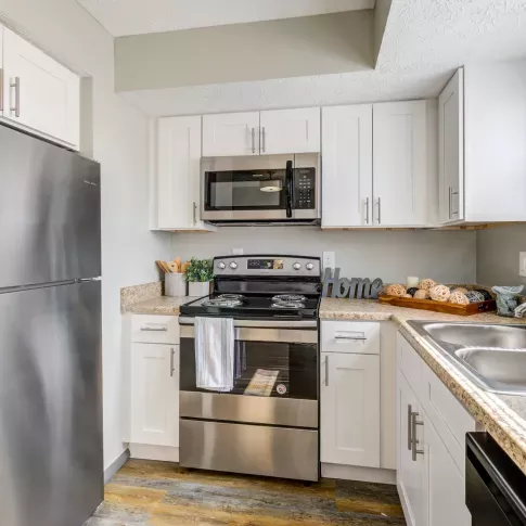 Fully equipped kitchen featuring stainless steel appliances, white cabinetry, and ample countertop space in Worthington Meadows Apartments.