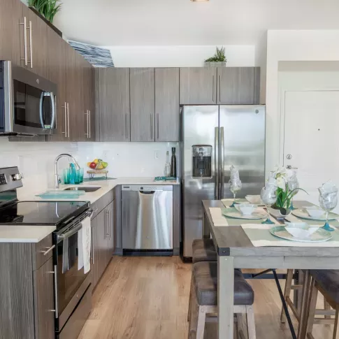 Modern kitchen at 275 Fontaine Parc Luxury Apartments featuring stainless steel appliances, sleek wood cabinetry, and a stylish dining area with elegant place settings.
