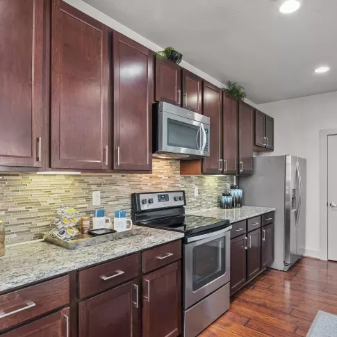 A modern kitchen with granite countertops, stainless steel appliances, and a tile backsplash in a luxury apartment at Arrabella Apartments.