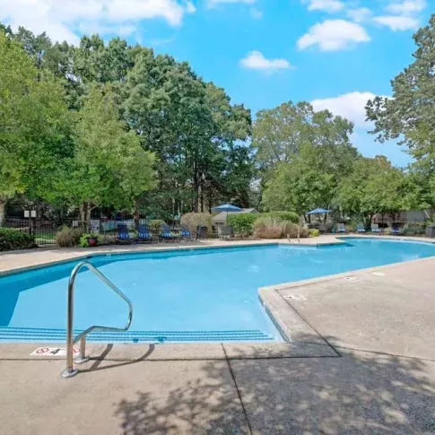 A large pool with crystal-clear water, surrounded by nature and ample seating.